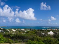 A panoramic view of Orient Bay from the great viewpoint in Paradise View restaurants parking lot. Pinel Island is off shore at left, then Tintamarre Island in the distance at centre and Green Caye just to the right of that. the coloured roofs on the right side at beach front are Orient Village.